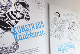 Shot of two large canvases hanging next to each other on the wall. Both show illustrations of the character "Kurti" in different settings: Riding a horse as well as posing for a painter in the Allgäu landscape. Cyan-coloured lettering is placed on the illustrations.