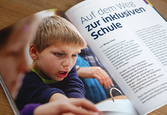 Detail photo of a double page spread with an article. On the right side the headline "On the way to an inclusive school", next to it a portrait photo of a blind child reading at school.