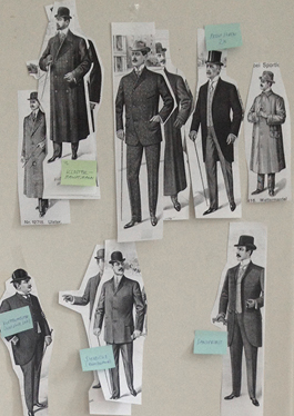The photo shows a shot from the working process. It shows cut-out black and white print-outs of drawings of historical male fashion figures of the 19th century pinned to a wall. The cut-out figures are pasted with blue and green Post-It notes.