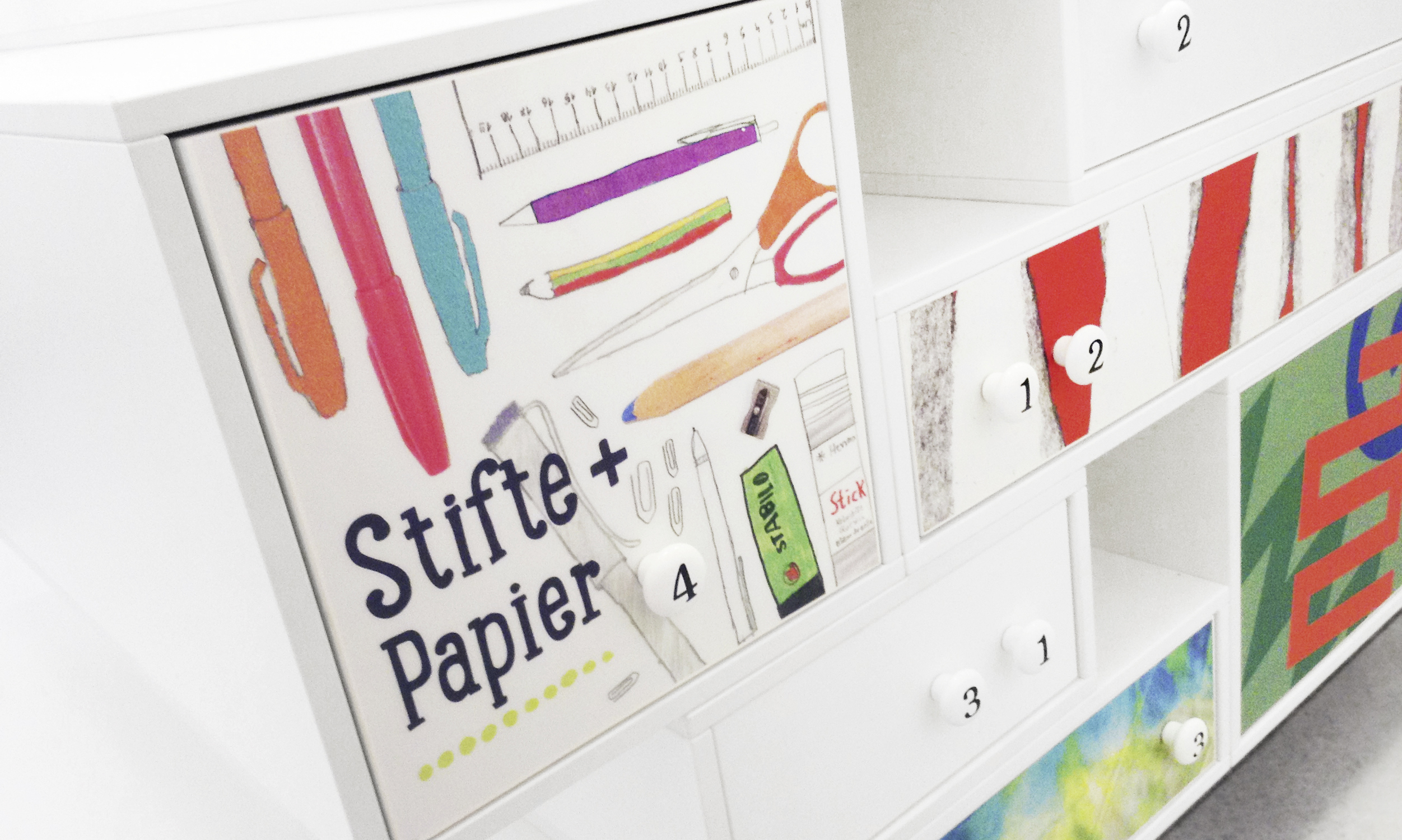 Close-up of the experience room. The picture shows a drawer designed with illustrations of pens, scissors, glue sticks and other