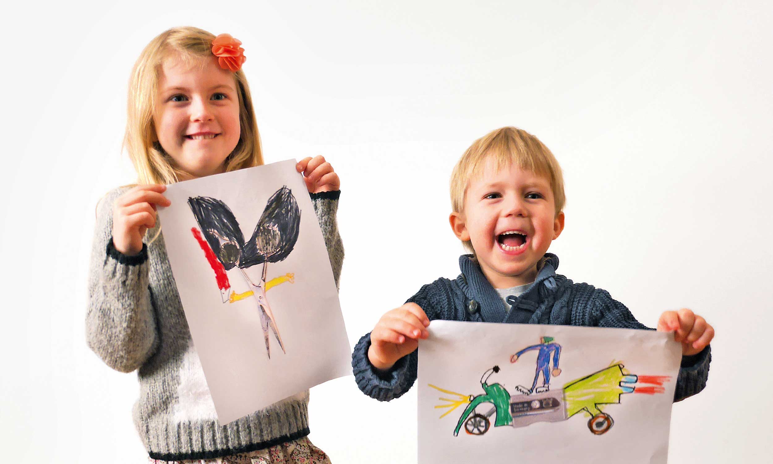 Two children proudly hold their self-painted pictures in their hands.