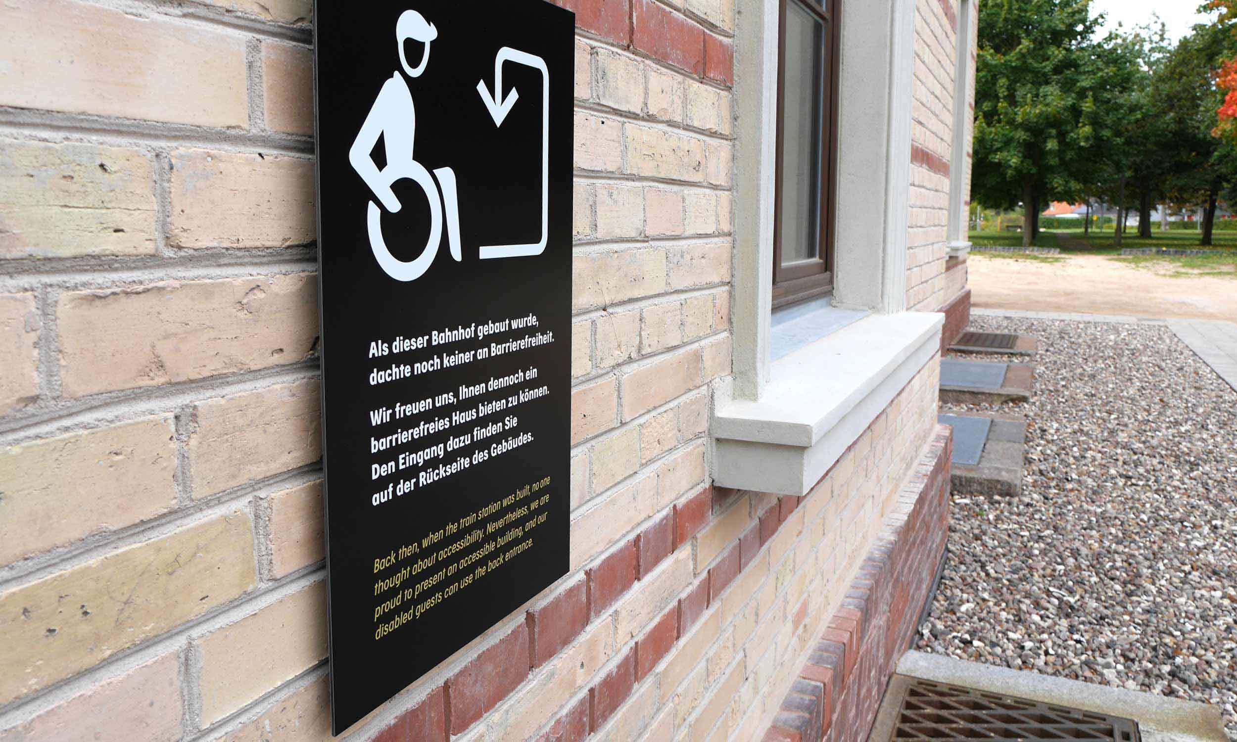 Foto eines Hinweisschildes mit Informationen zum Eingang für Rollstuhlfahrer
