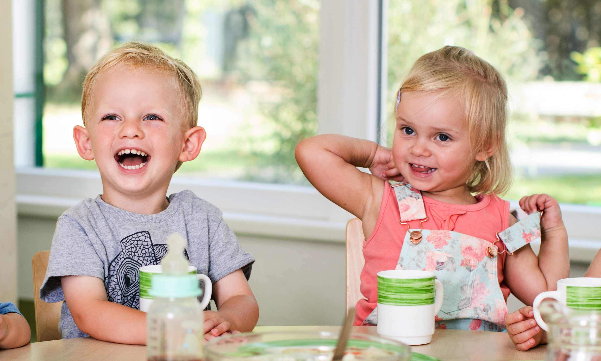Foto zweier lachender Kita-Kinder am Vesper-Tisch