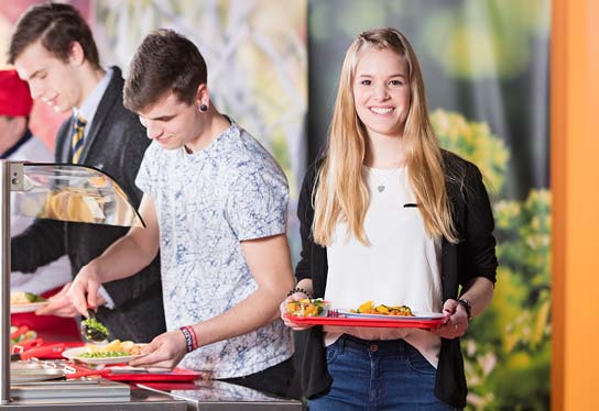 Photo of three pupils helping themselves to the lunch menu at a serving counter