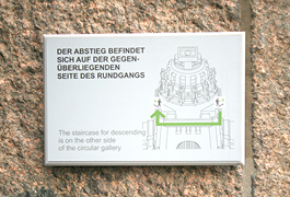 A small information board showing a detailed drawing of the building's dome is mounted on one wall of the stone masonry.