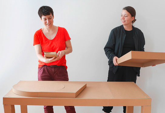 Foto, auf dem unsere Mitarbeiterinnen Franziska und Mia das Funktionsmodell der Taststation in Originalgröße aus Pappe zusammensetzen