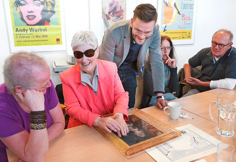 Photo with blind and visually impaired test readers examining the tactile painting "The Little Princess".