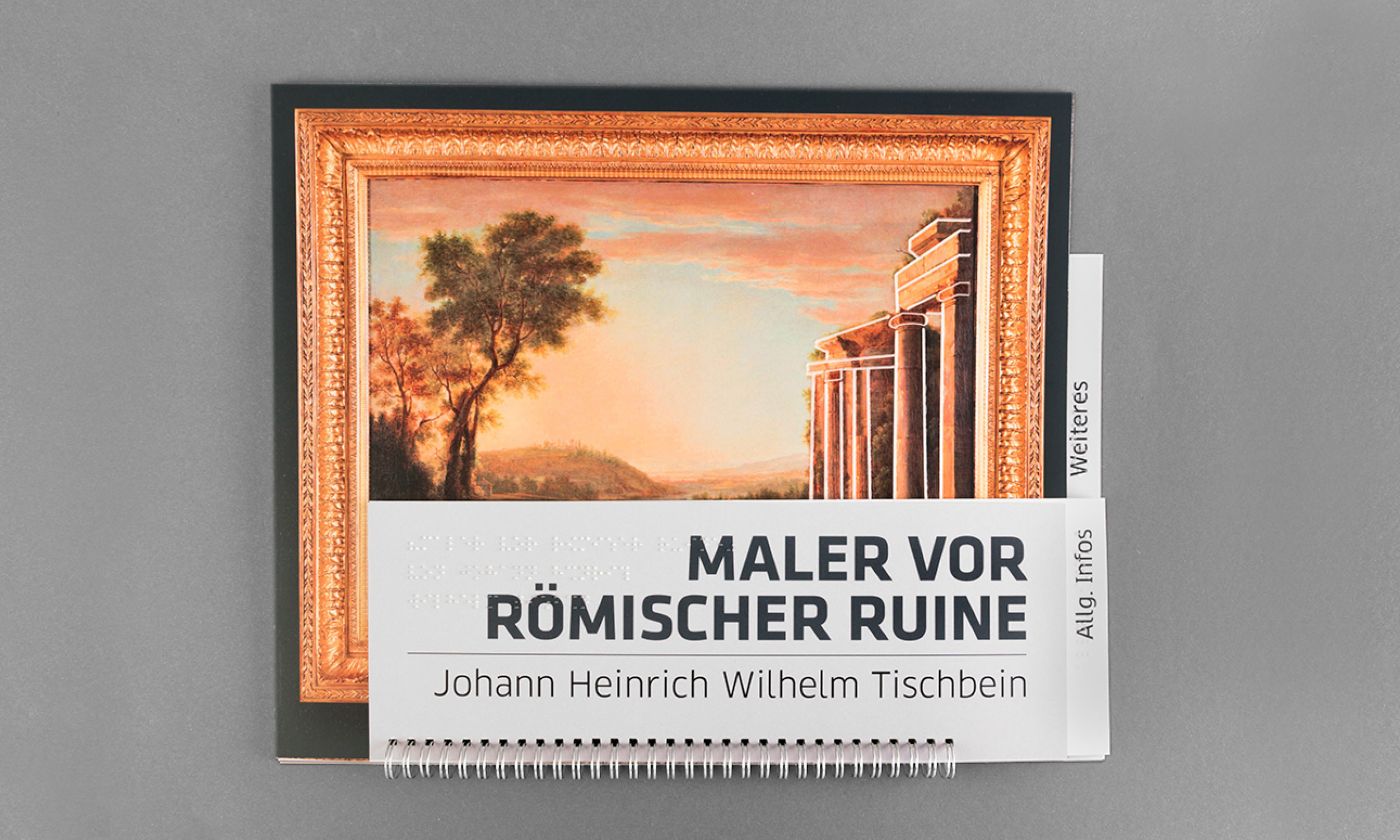 Photo of the tactile booklet accompanying the painting "Painter in front of a Roman ruin" on grey tabletop