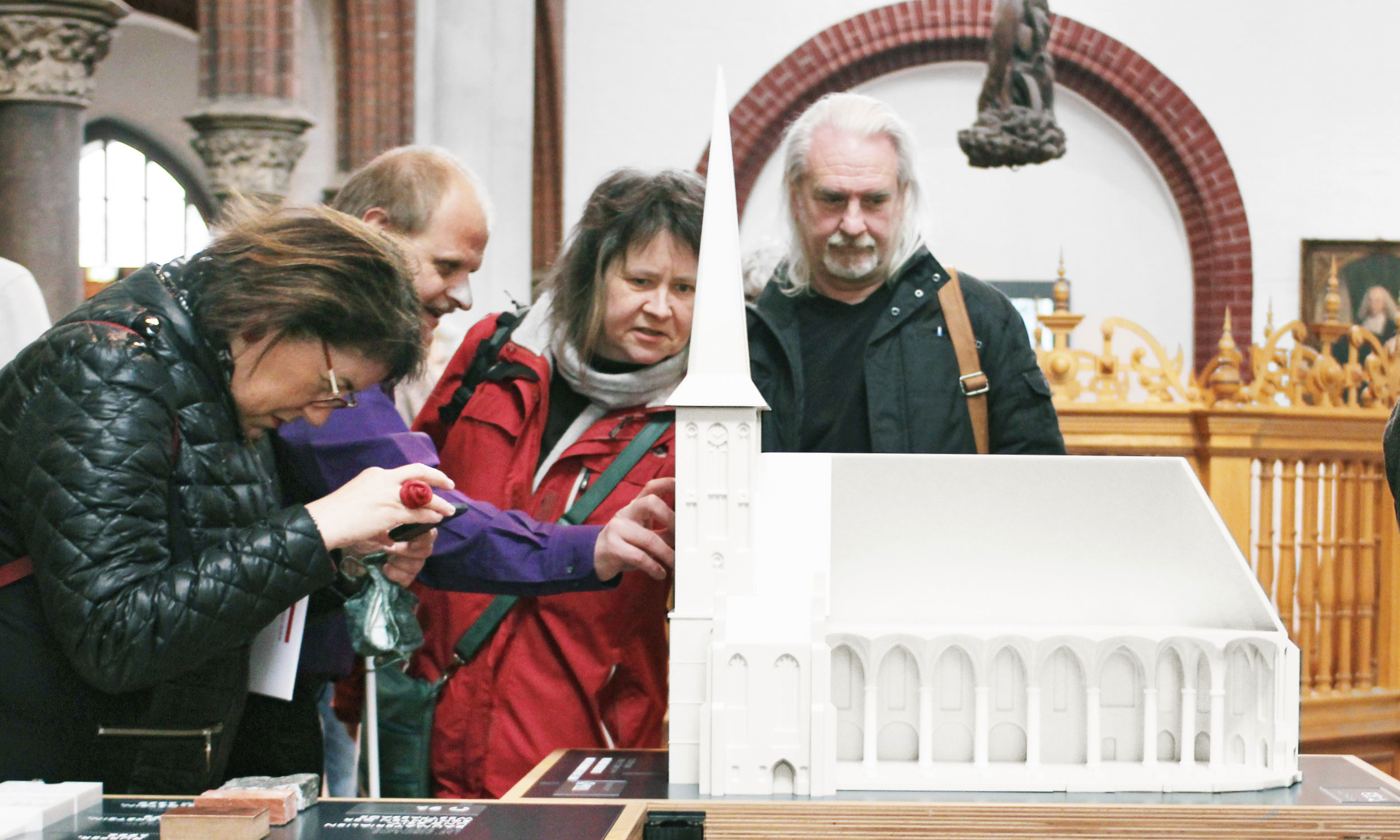 Sehende und blinde Besucher begutachten bei der Eröffnung das große Modell der Nikolaikirche.