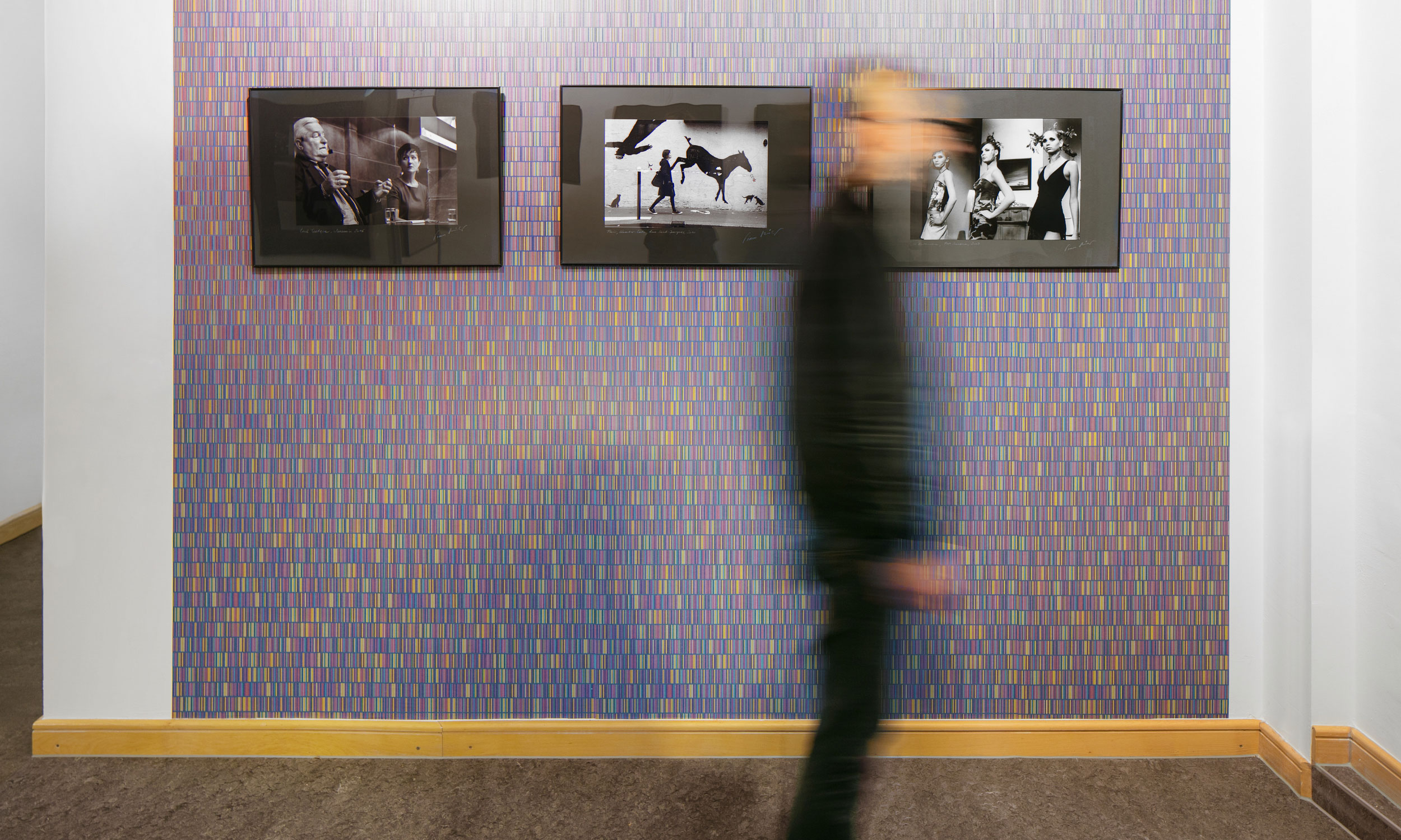 Foto mit Blick auf eine Wandfläche bestehend aus einem Teppich farbiger Stäbchen in einem Durchgangsflur