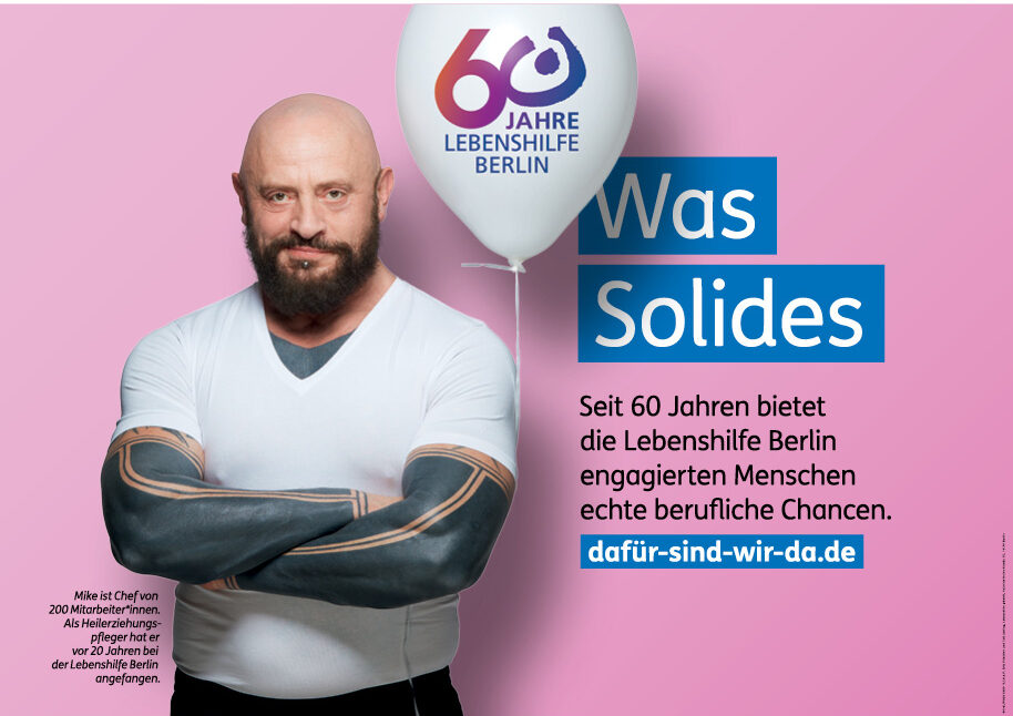Large poster of the motif "Something solid", which shows a tattooed, muscular man who has developed from a Curative Education Worker to a current senior staff member of Lebenshilfe