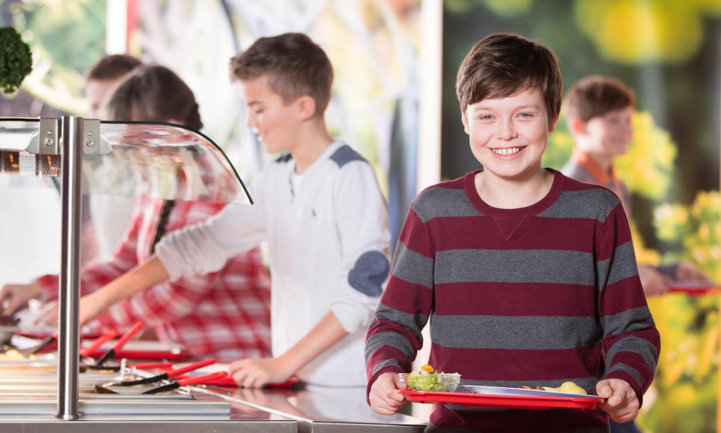 Photo of a boy with lunch on a tray that he has just put together at a self-service counter