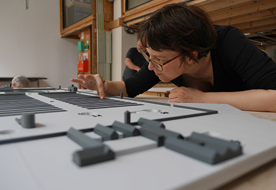 Eine Mitarbeiterin von inkl Design beim genauen Betrachten der ausgebauten Modellplatte des Tastmodells