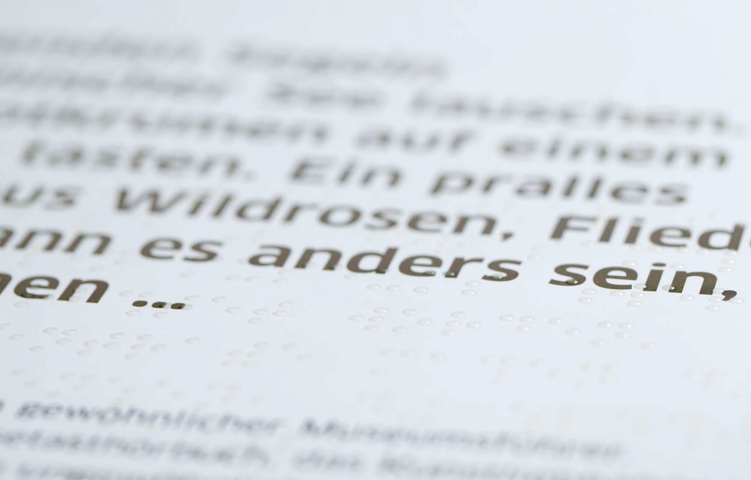 Detailfoto eines Braille-Druckes mit transparentem Lack auf Schwarzdruck. Das Braille-Schriftbild ist sauber ausgearbeitet und gut lesbar.