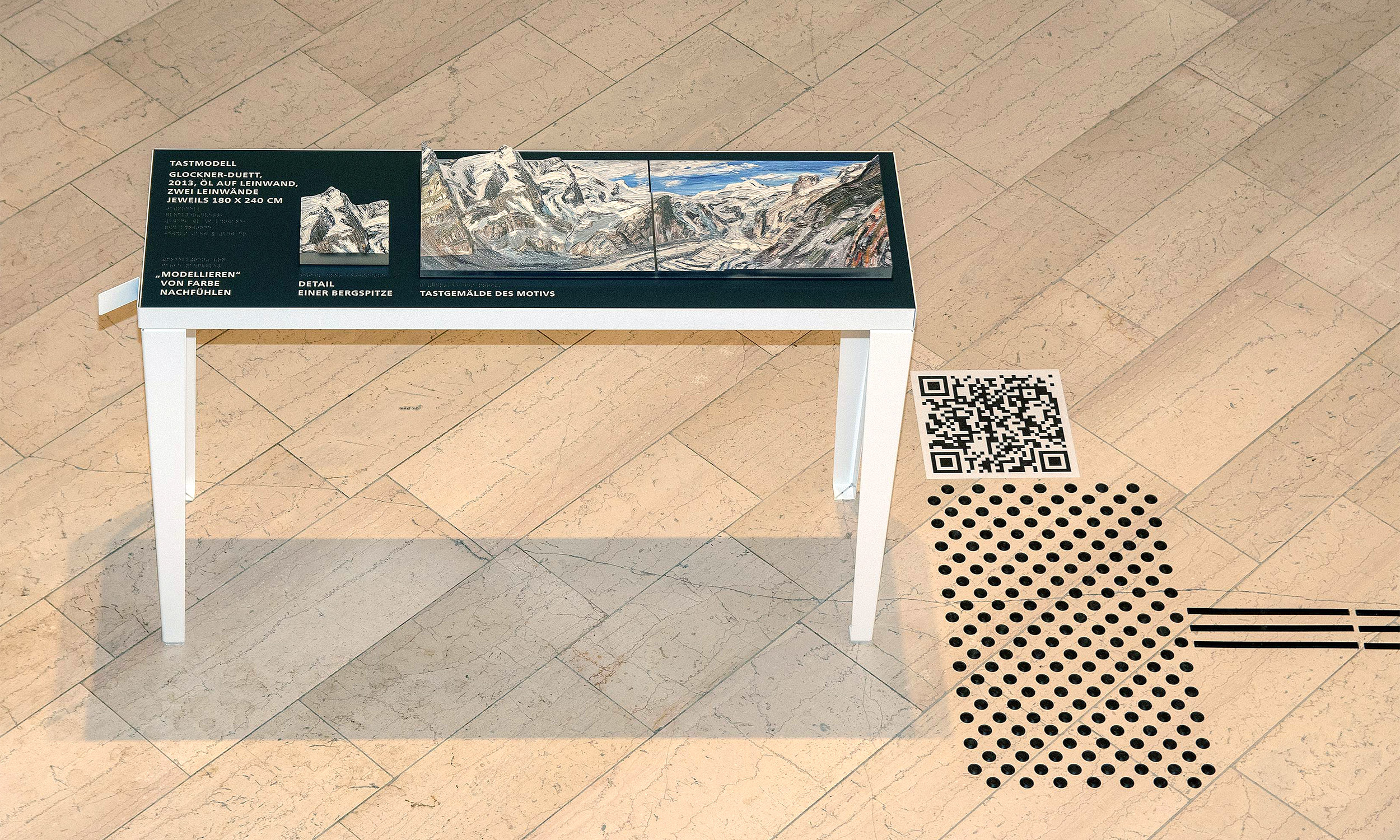 View from above of the entire table with tactile model for the painting "Bergwelten". On the right is an attention field and a QR code.