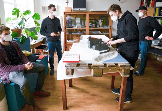 Links eine Aufnahme aus dem Büro von inkl.Design: das Team begutachtet eines der dreidimensionalen Modelle.