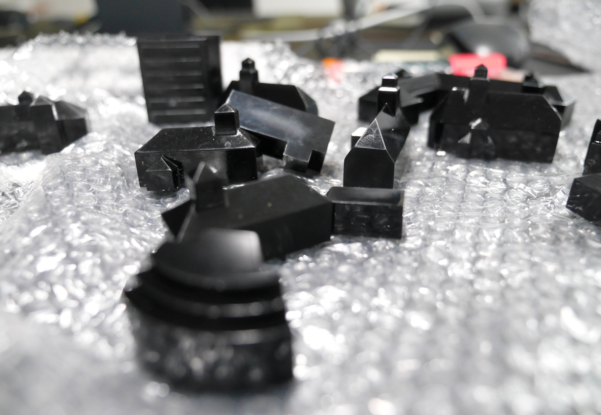 Several of the black three-dimensional buildings lie on a plastic sheet.