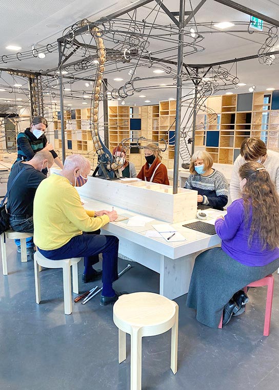 Another photo shows members of the focus group in the Weltstudio. They are trying out different activities, for example stamps or writing stencils.