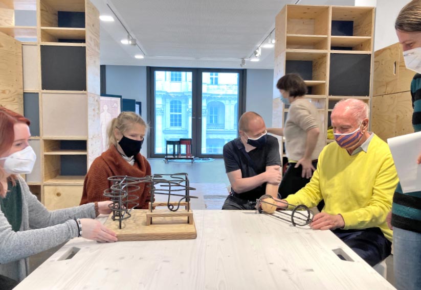 Members of the focus group sit at a table in the Humboldt Forum and feel a model of the Rolling Cathographer.