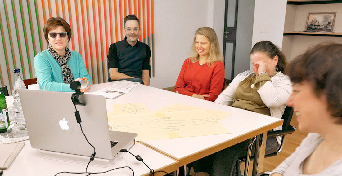 Drei blinde Frauen aus der Fokusgruppe und zwei Mitarbeiter von inkl. Design sitzen lachend um ein geöffnetes Laptop herum. Wegen der Coronapandemie finden gemeinsame Treffen online statt.