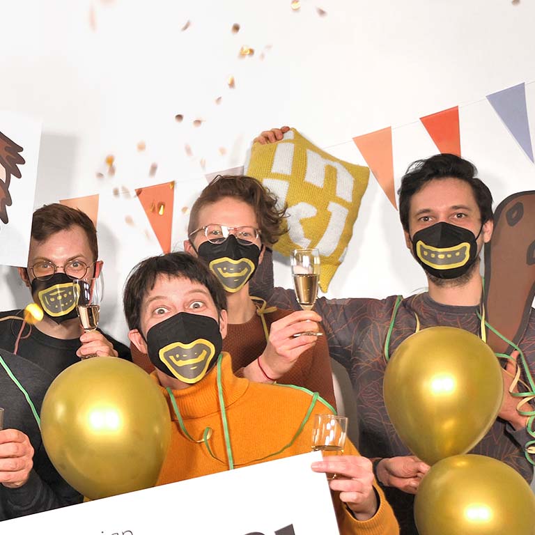 A detail from a larger photo shows four inkl designers happily, with champagne glasses in their hands and golden balloons