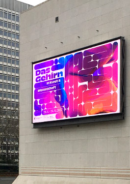 Außenansicht der Bundeskunsthalle Bonn. Auf der Fassade ist ein digitales Werbeschild, welches die Ausstellung „Das Gehirn“ bewirbt.